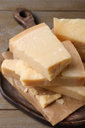 Photo of Pieces of parmesan cheese on wooden table, closeup