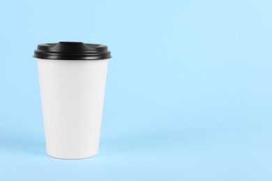 Photo of Paper cup with plastic lid on light blue background, space for text. Coffee to go