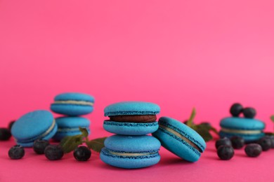 Photo of Delicious macarons, mint and blueberries on pink background, space for text