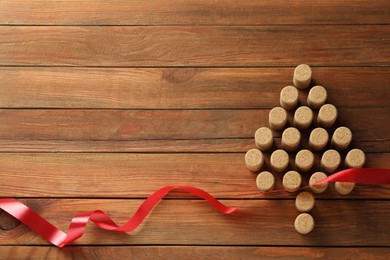 Photo of Christmas tree made of wine corks and red ribbon on wooden table, top view. Space for text