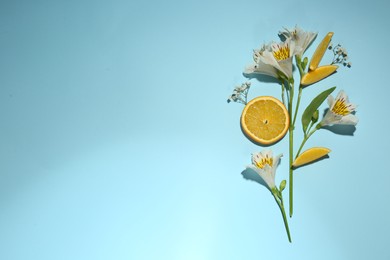 Photo of Flat lay composition with alstroemeria flowers and orange slices on light blue background, space for text