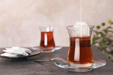 Photo of Brewing tea with bag in traditional Turkish cup on table. Space for text