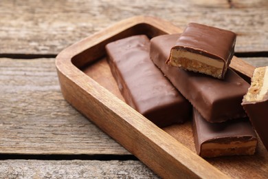Photo of Tasty chocolate bars with nougat on wooden table, closeup