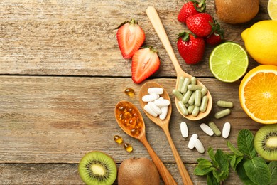 Photo of Different vitamin pills and fresh fruits on old wooden table, flat lay. Space for text