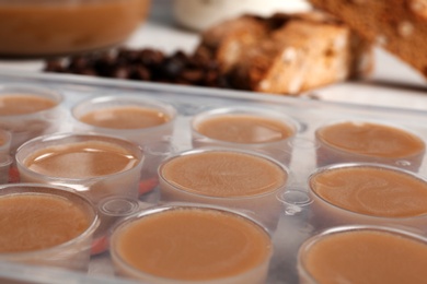 Photo of Ice cube tray filled with coffee drink on table, closeup