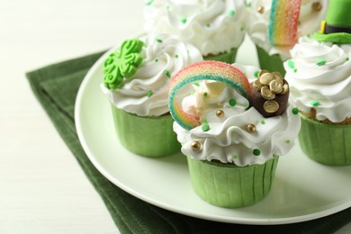 Photo of St. Patrick's day party. Tasty festively decorated cupcakes on white table, closeup