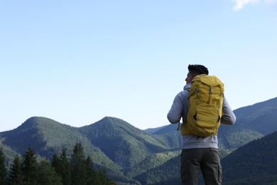 Photo of Tourist with backpack enjoying mountain landscape, back view. Space for text