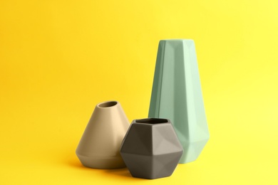 Photo of Stylish empty ceramic vases on yellow background