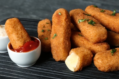 Photo of Cheese sticks and sauce on board, closeup