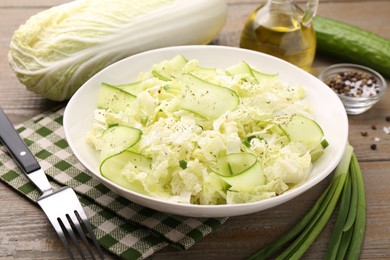 Photo of Tasty salad with Chinese cabbage, cucumber and green onion in bowl on wooden table, closeup