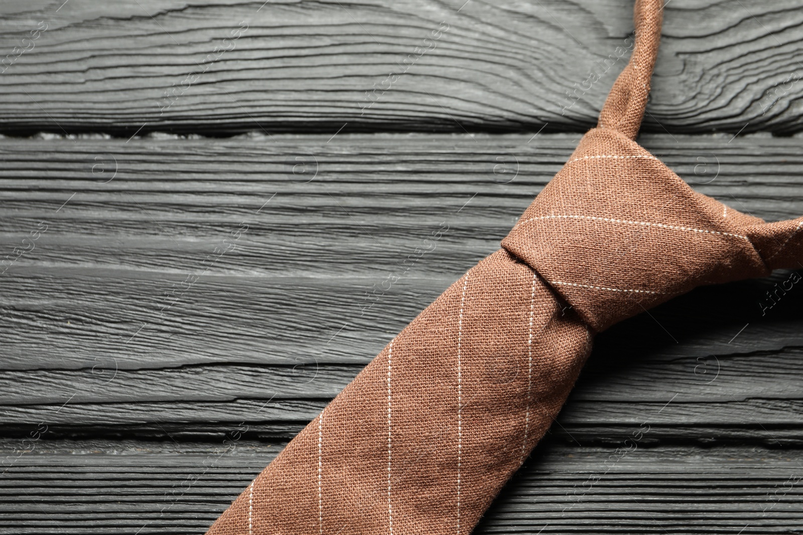 Photo of One striped necktie on black wooden table, top view. Space for text