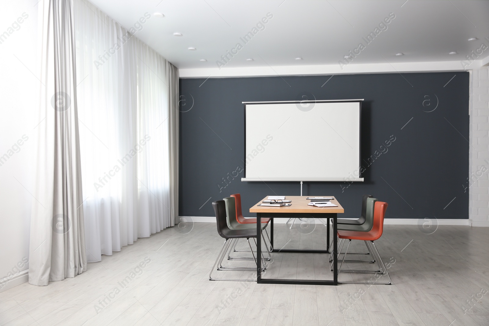 Photo of Modern meeting room interior with large table and projection screen