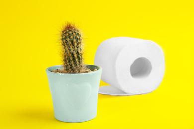 Photo of Roll of toilet paper and cactus on yellow background. Hemorrhoid problems