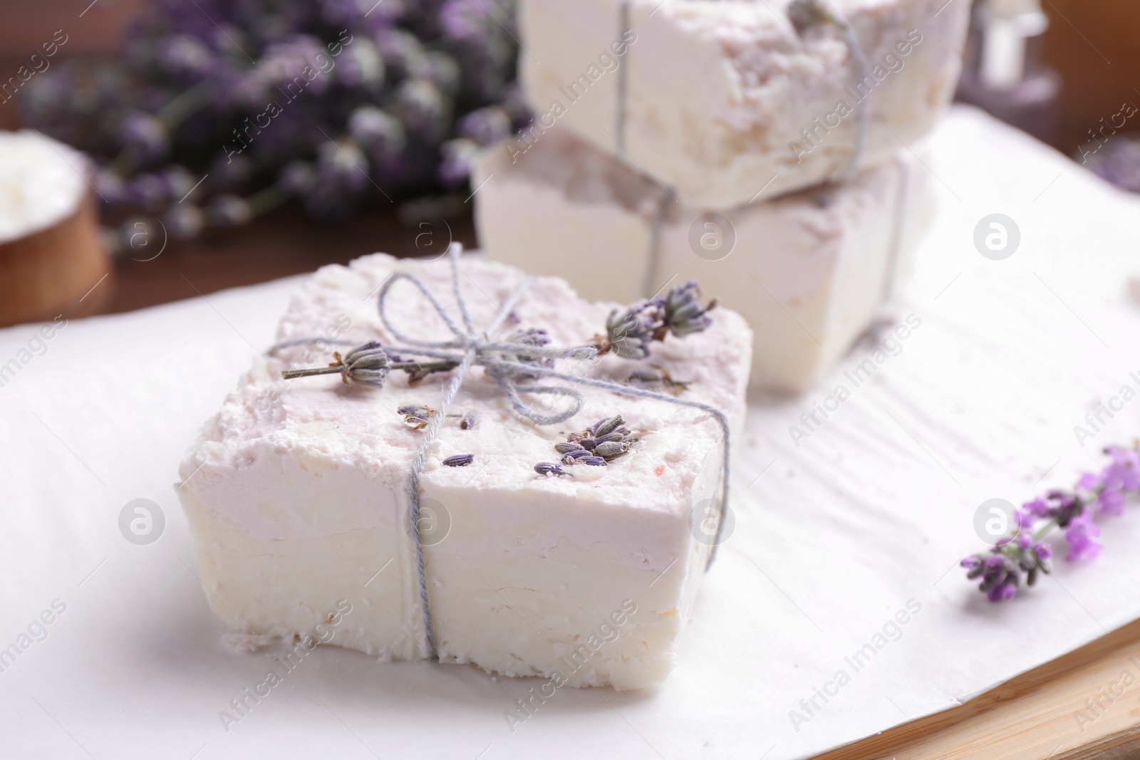 Photo of Hand made soap bars with lavender flowers on white paper, closeup