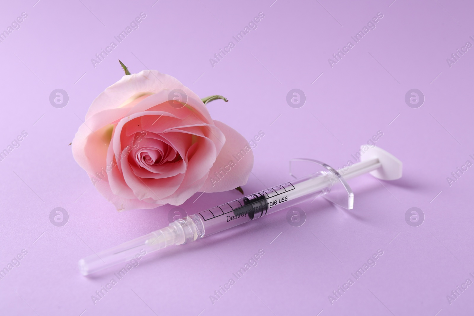 Photo of Cosmetology. Medical syringe and rose flower on violet background