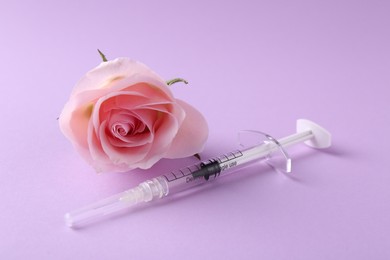 Cosmetology. Medical syringe and rose flower on violet background