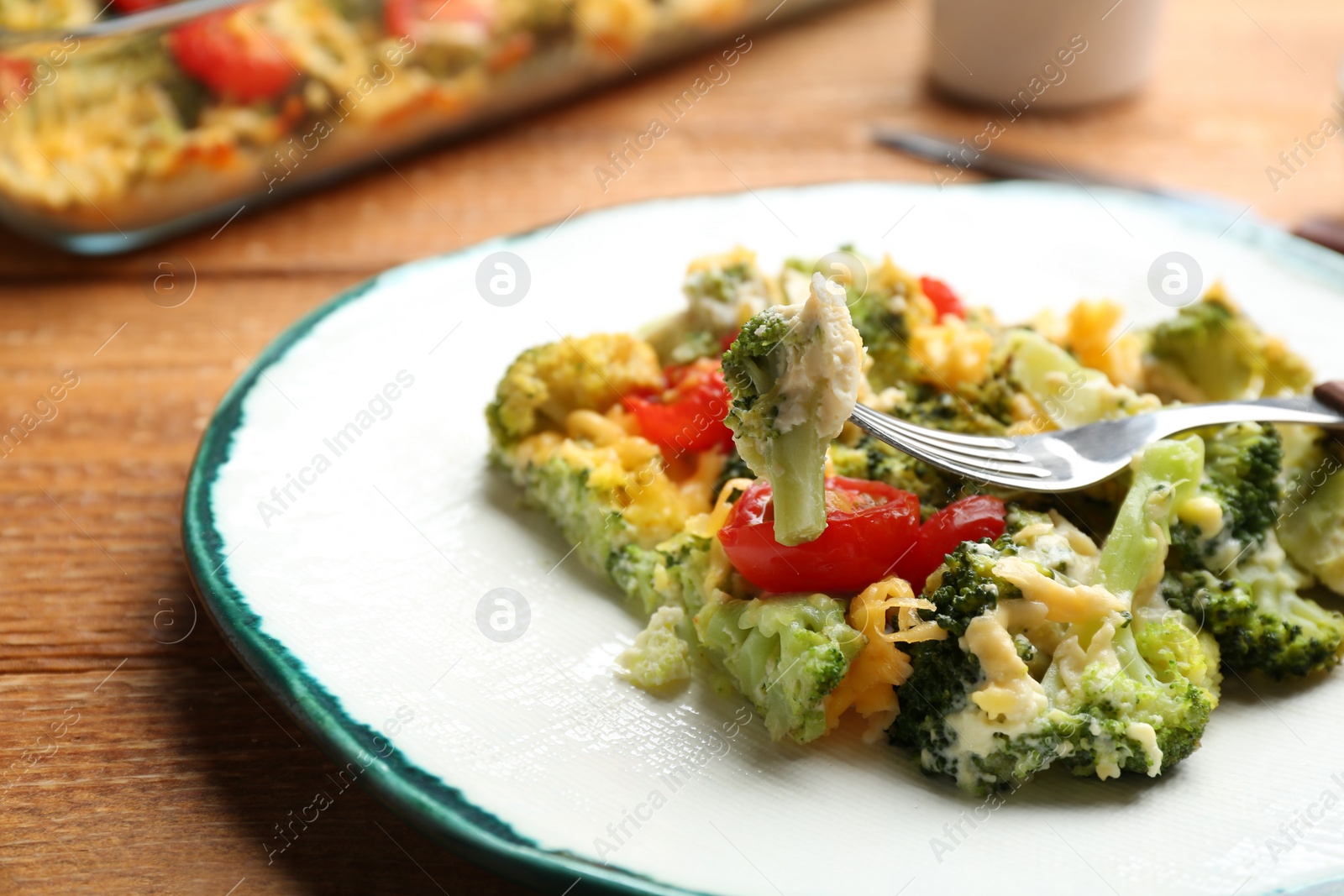 Photo of Tasty broccoli casserole served on wooden table, closeup