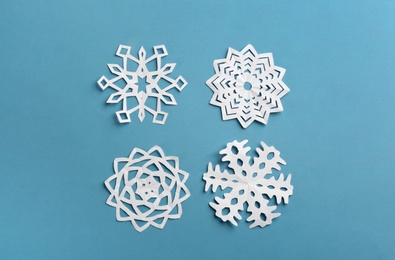 Photo of Many paper snowflakes on turquoise background, flat lay