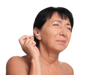 Senior woman cleaning ear with cotton swab on white background