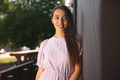 Photo of Beautiful young woman in stylish violet dress outdoors