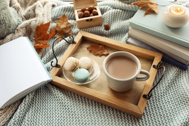 Photo of Tray with breakfast near stack of books on knitted plaid