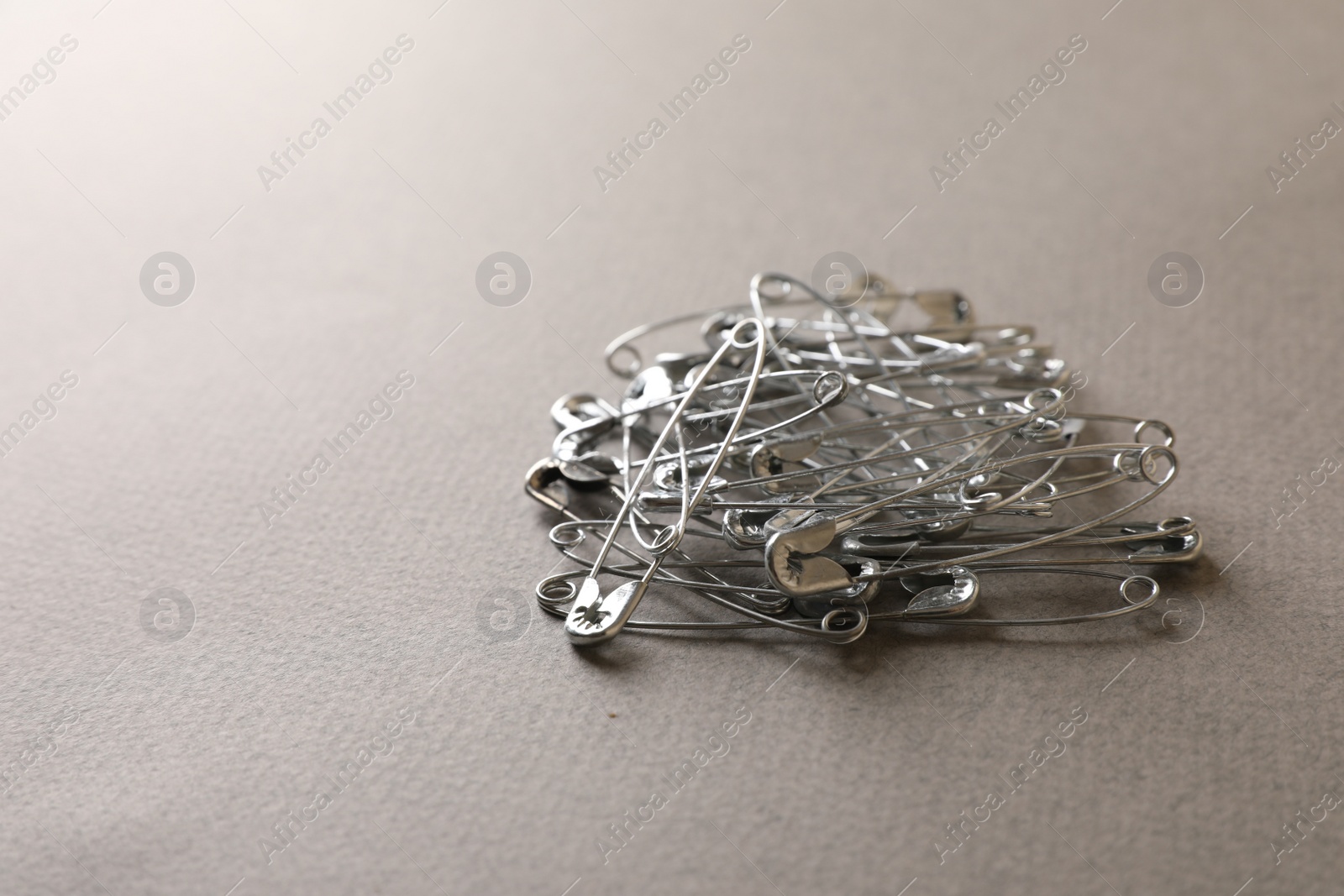 Photo of Pile of safety pins on light grey textured background, space for text