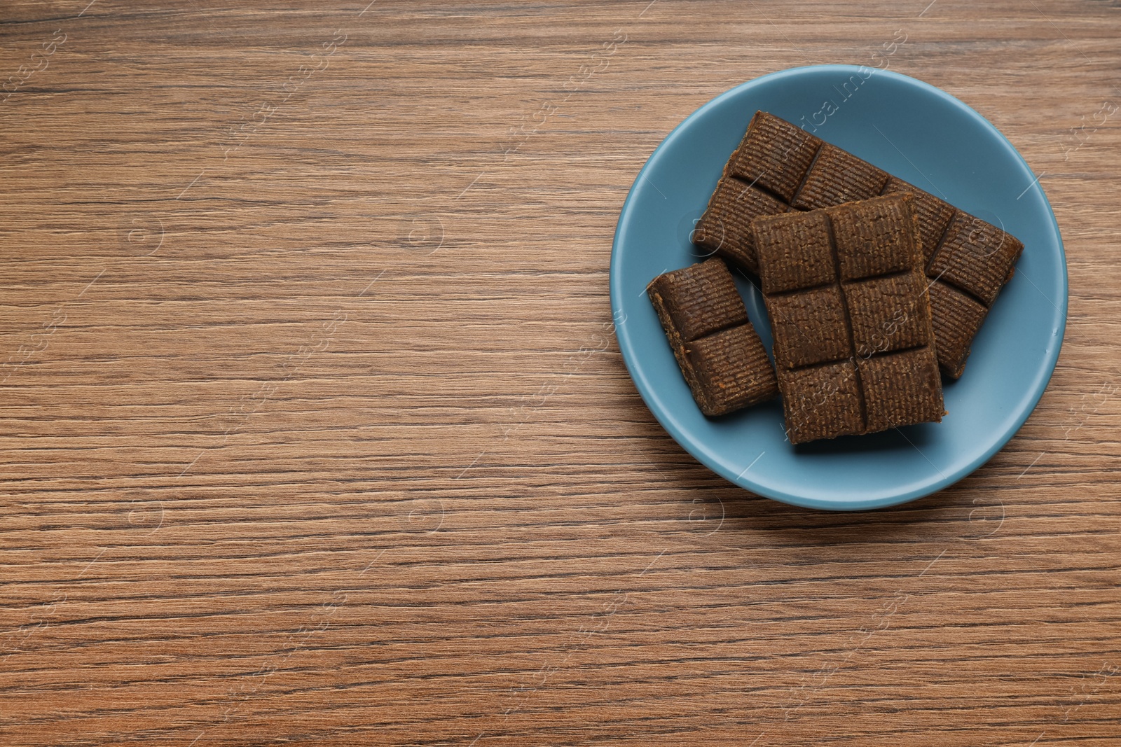 Photo of Blue plate with delicious and healthy hematogen on wooden table, top view. Space for text