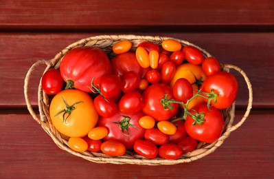 Photo of Wicker basket with fresh tomatoes on wooden table, top view