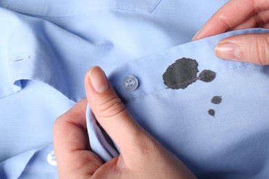 Woman holding shirt with black ink stain, closeup