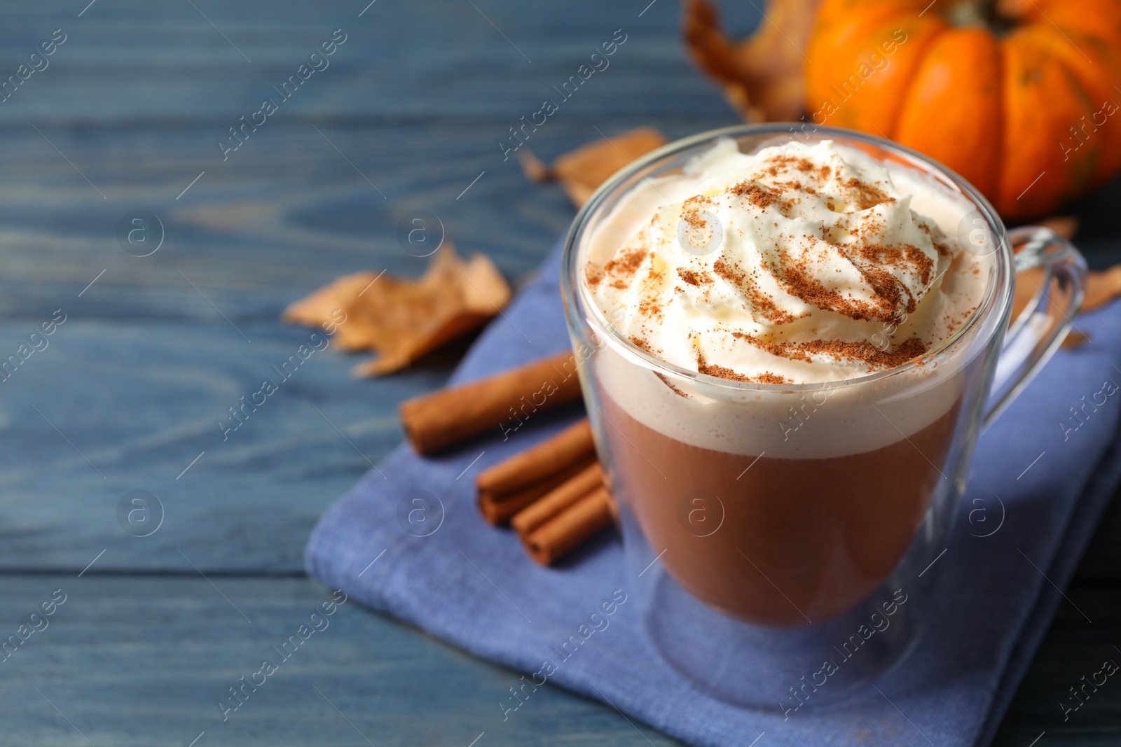 Photo of Delicious pumpkin latte on blue wooden table, closeup. Space for text