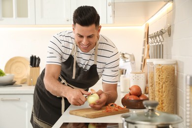 Photo of Man peeling onion at kitchen counter. Preparing vegetable