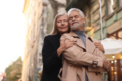Photo of Portrait of affectionate senior couple on city street, low angle view. Space for text
