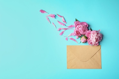 Beautiful peony flowers and envelope on color background