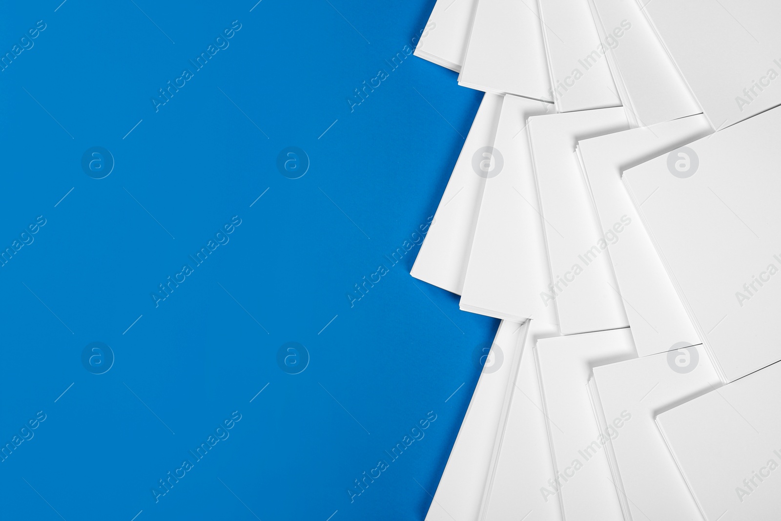 Photo of Many stacks of paper sheets on blue background, flat lay. Space for text