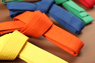 Photo of Colorful karate belts on brown background, closeup