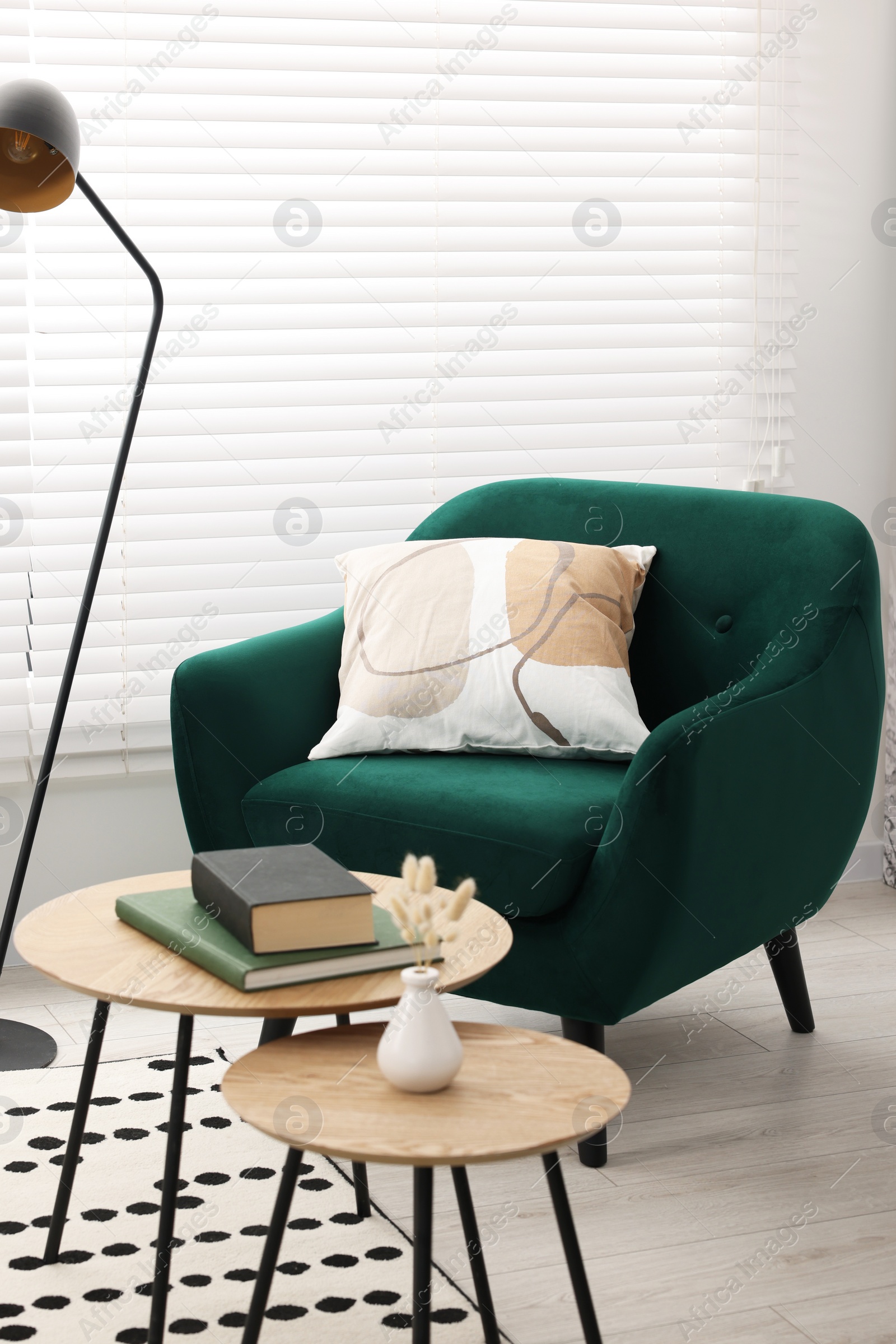Photo of Comfortable armchair, lamp and nesting tables in stylish room