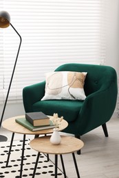 Photo of Comfortable armchair, lamp and nesting tables in stylish room