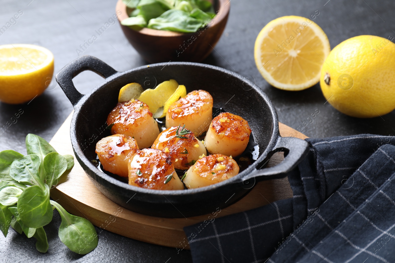 Photo of Delicious fried scallops, lemons and corn salad on dark gray textured table