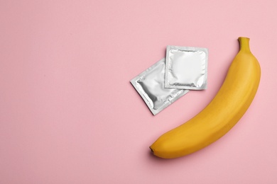 Photo of Condoms with banana and space for text on pink background, flat lay. Safe sex