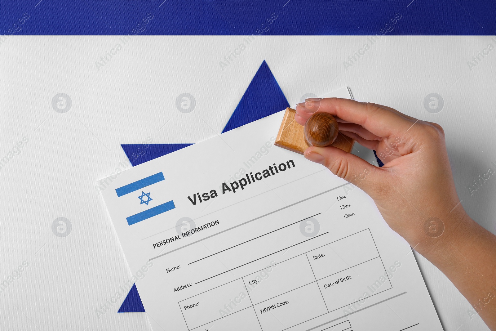 Photo of Immigration to Israel. Woman stamping visa application form on flag, top view
