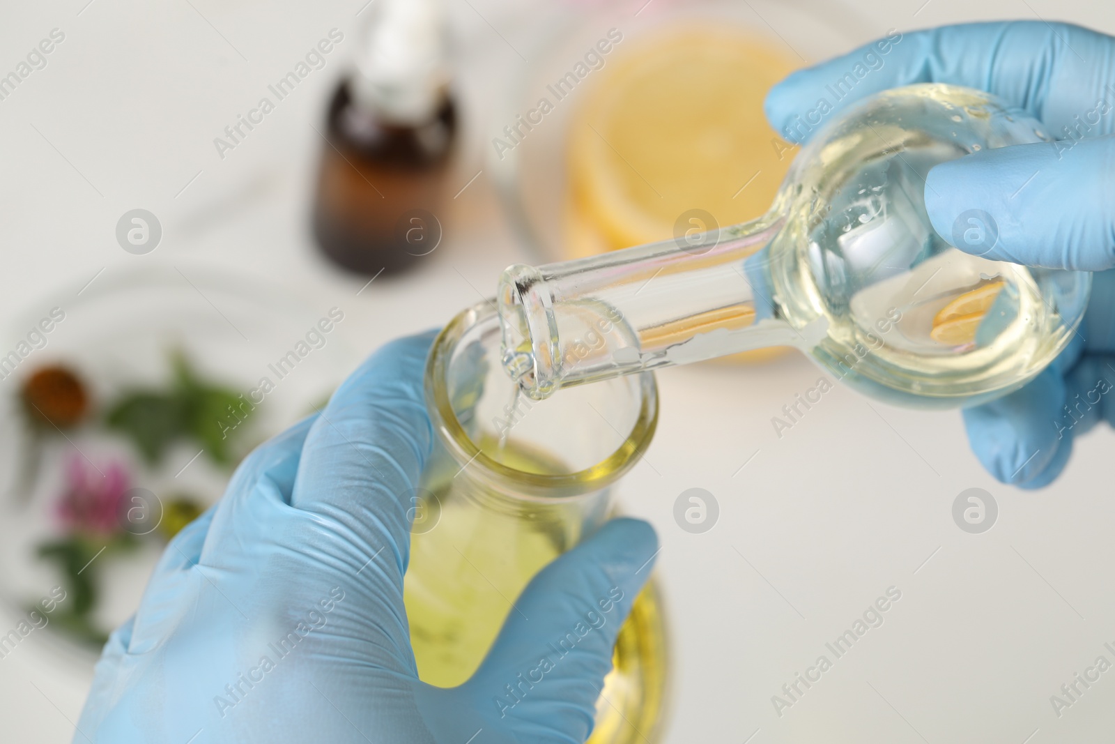 Photo of Scientist in medical gloves developing cosmetic oil, closeup view