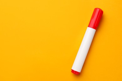 Bright red marker on orange background, top view. Space for text