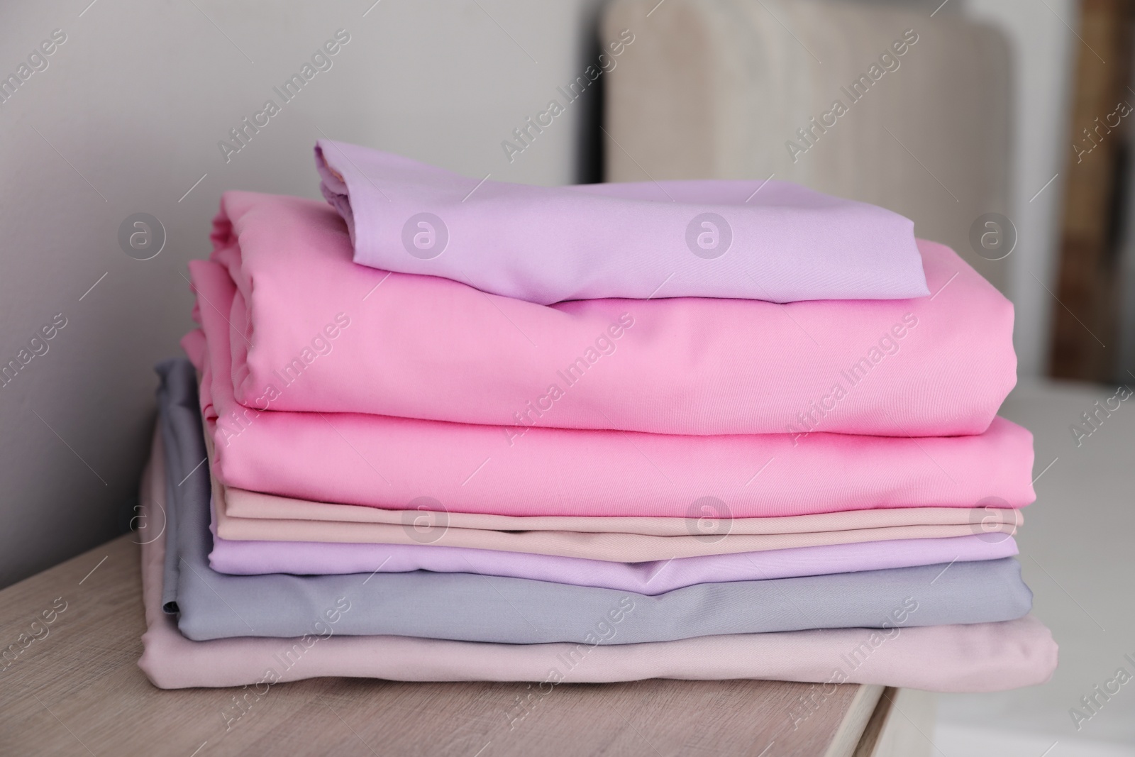 Photo of Clean color bed linens on wooden cabinet indoors