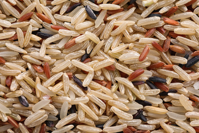 Photo of Mix of different brown rice as background, top view
