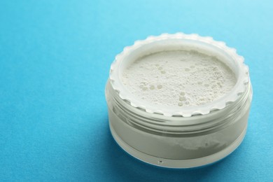 Photo of Rice loose face powder on light blue background, closeup. Space for text