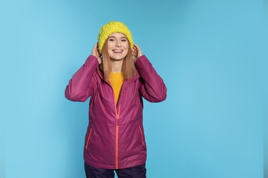 Young woman wearing warm clothes on color background. Ready for winter vacation