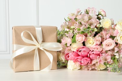 Photo of Happy Mother's Day. Gift box and bouquet of beautiful flowers on white table