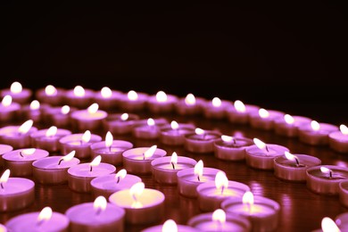 Image of Beautiful burning violet candles on black background. Funeral attributes