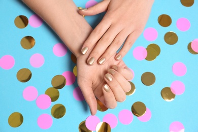 Photo of Woman with golden manicure on color background, top view. Nail polish trends