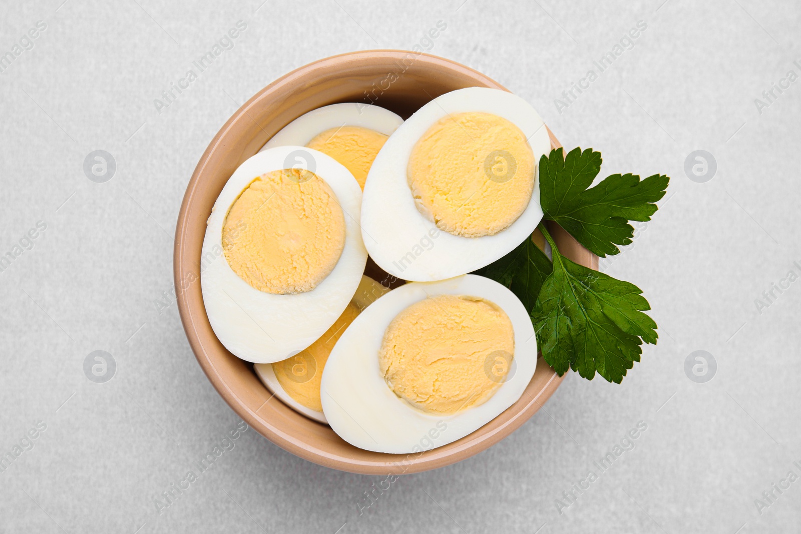 Photo of Fresh hard boiled eggs and parsley on light grey table, top view